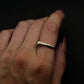 Hand wearing a gold bone ring on a dark background