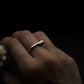 Gold bone ring on a finger against a dark background